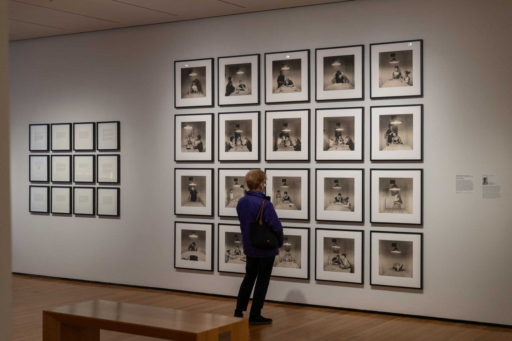 Visitor looks at 5x5 grid of framed photographs, mounted on gallery wall