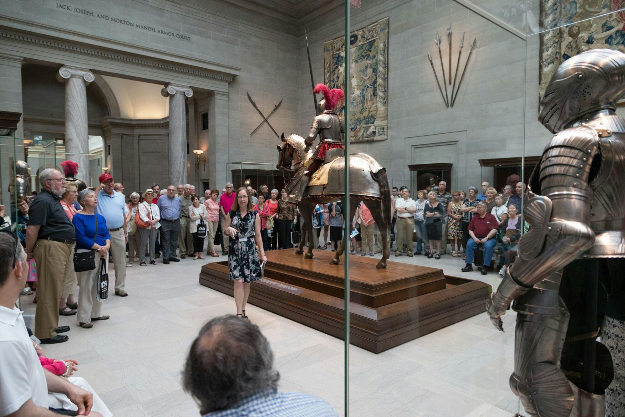 A tour guide leading a group of visitors through the armor court