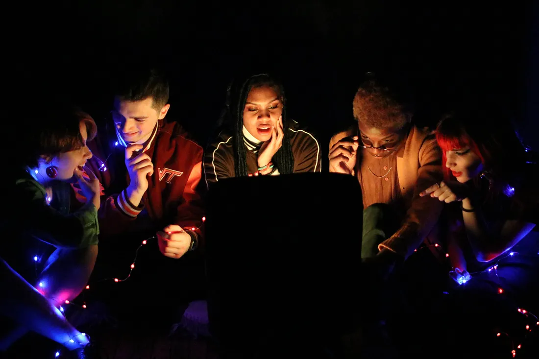 Teenagers gather in a semicircle in the dark.