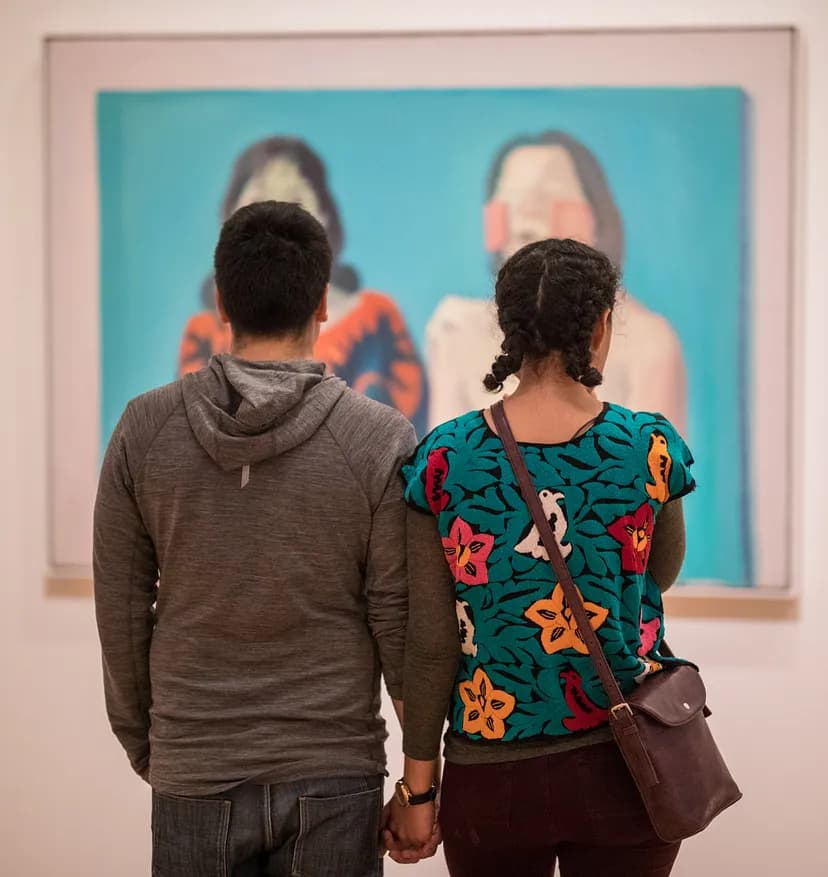 Two people holding hands and looking at a work of art.