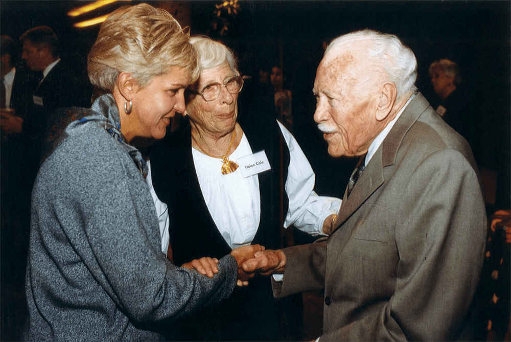 two women shaking man's hand