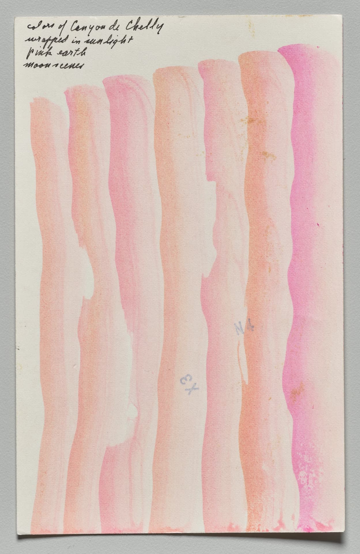Watercolor on vertically oriented paper creates seven thick, wavy vertical strokes in shades of pink, coral, and mauve. Against a light background, these irregular bands overlap, showing variations in saturation. Handwritten text in the upper left reads, "colors of Canyon de Chelly wrapped in sunlight pink earth moonscenes." Small blue notations, "X3" and "N4," are written within the central strokes.