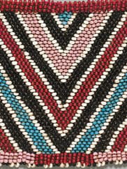 Close-up of a beaded panel with a "V" pattern alternating dark blue outlined with white and pink, red, and light blue.