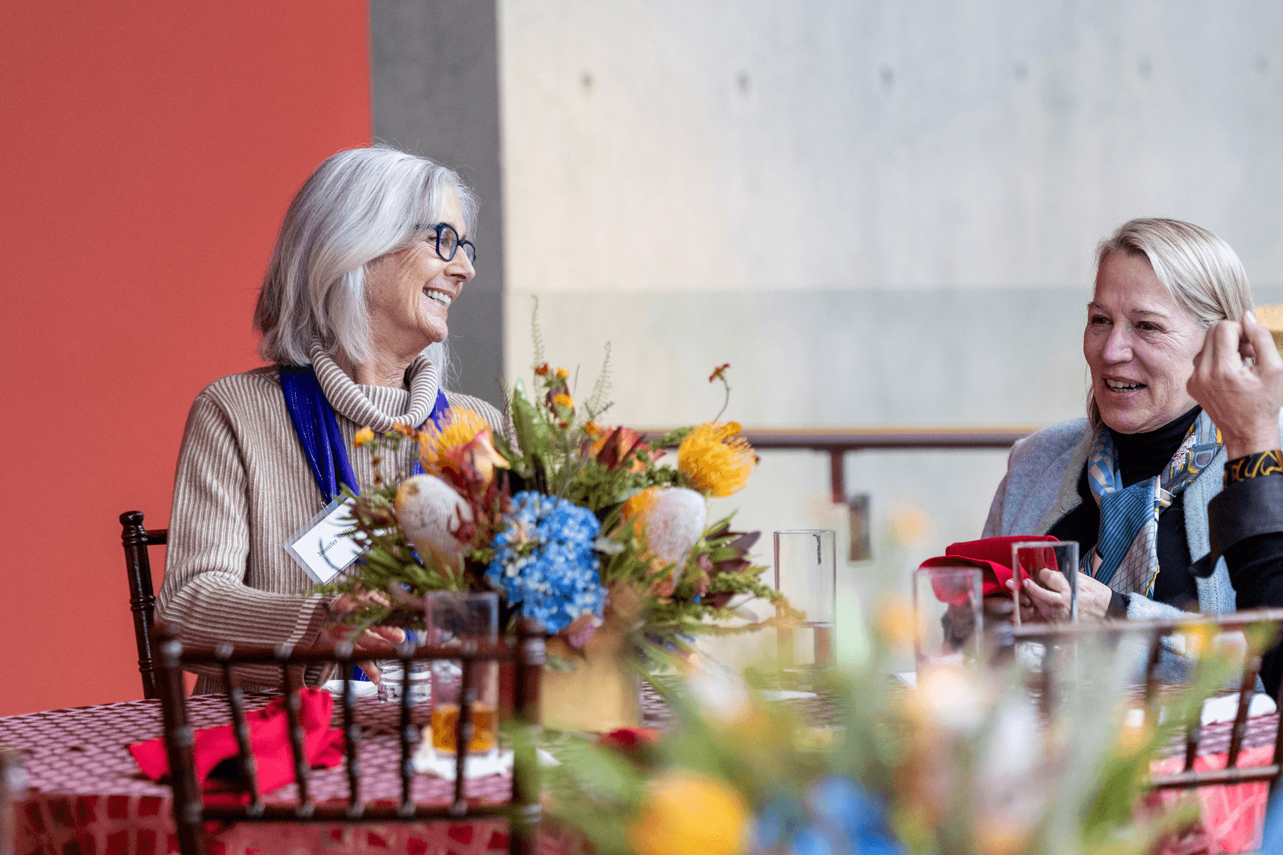 a couple of women sitting at a table with flowers