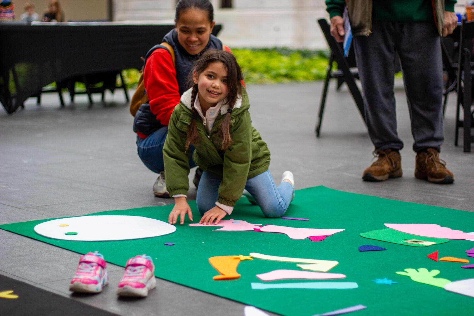 a boy and girl sitting on the ground with a green mat
