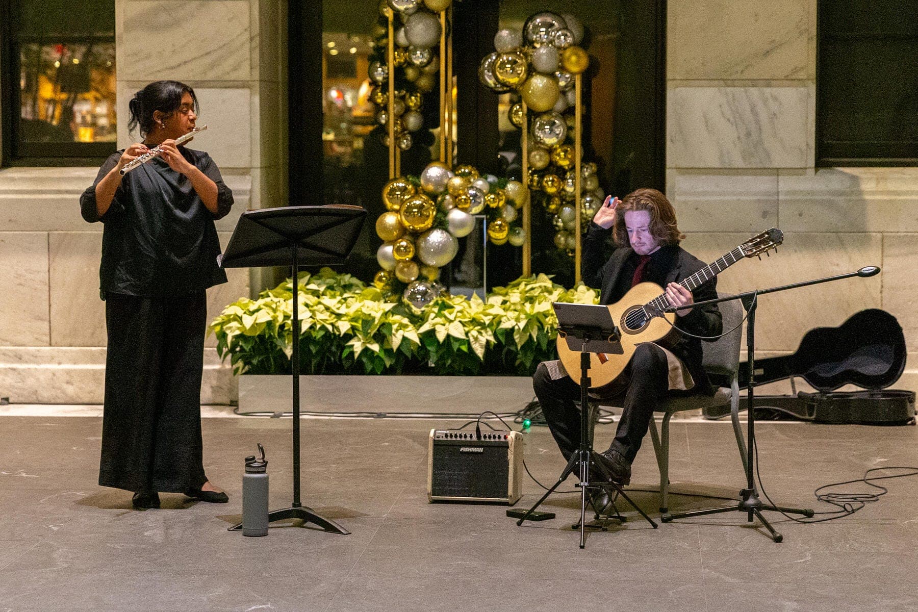 a man playing a guitar next to a woman playing a musical instrument