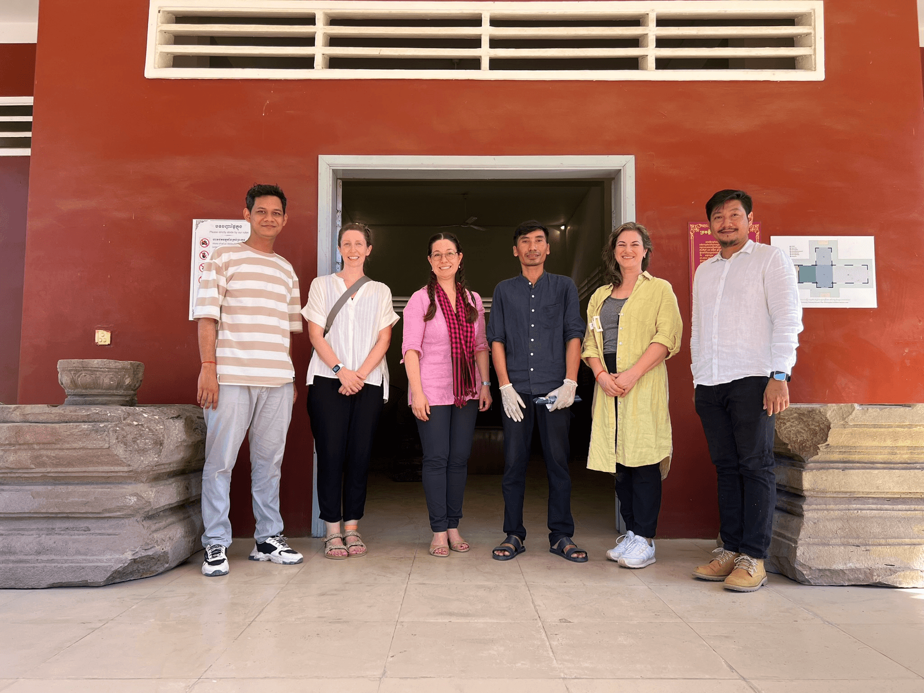 Six people standing in front of a red building in Cambodia