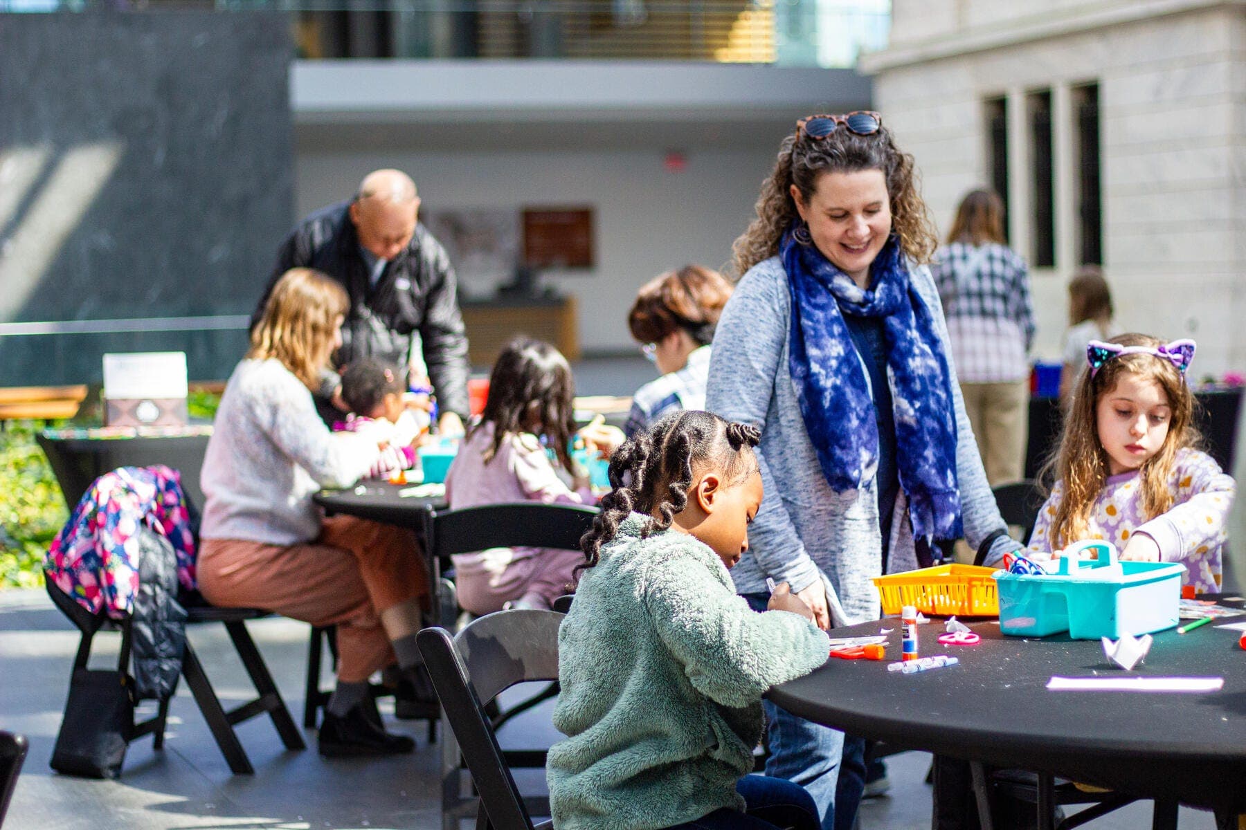A group of people making art while sitting at tables in the atrium of The Cleveland Museum of Art.