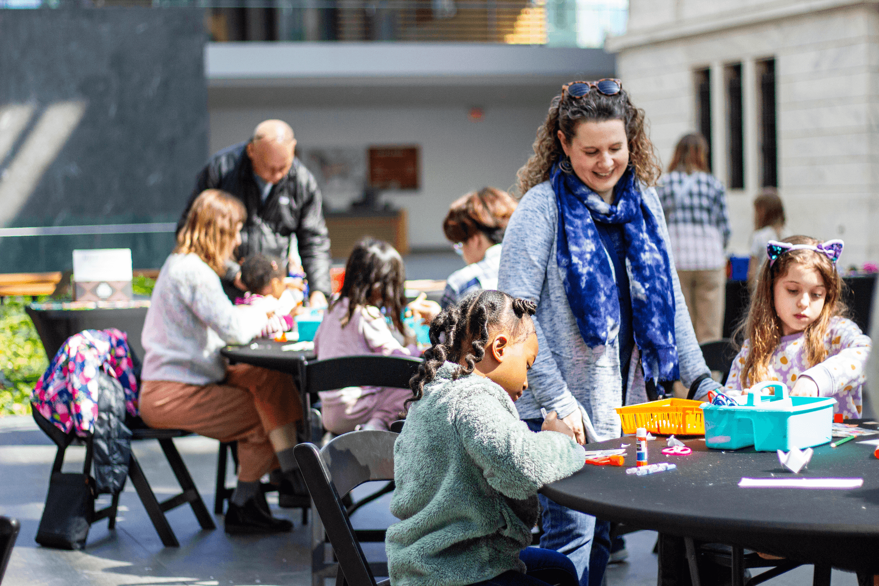 A group of people making art while sitting at tables in the atrium of The Cleveland Museum of Art.