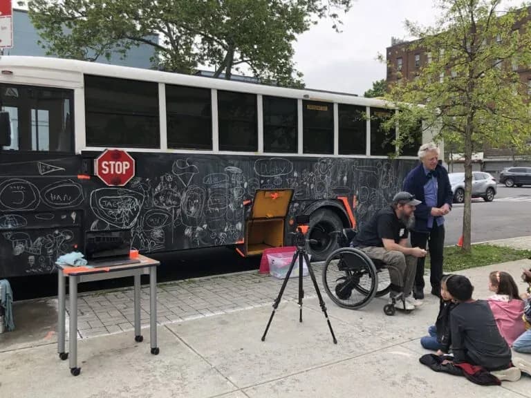 a group of people sitting on a bench next to a bus