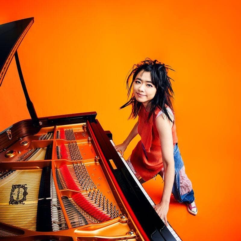 Hiromi sitting on a guitar