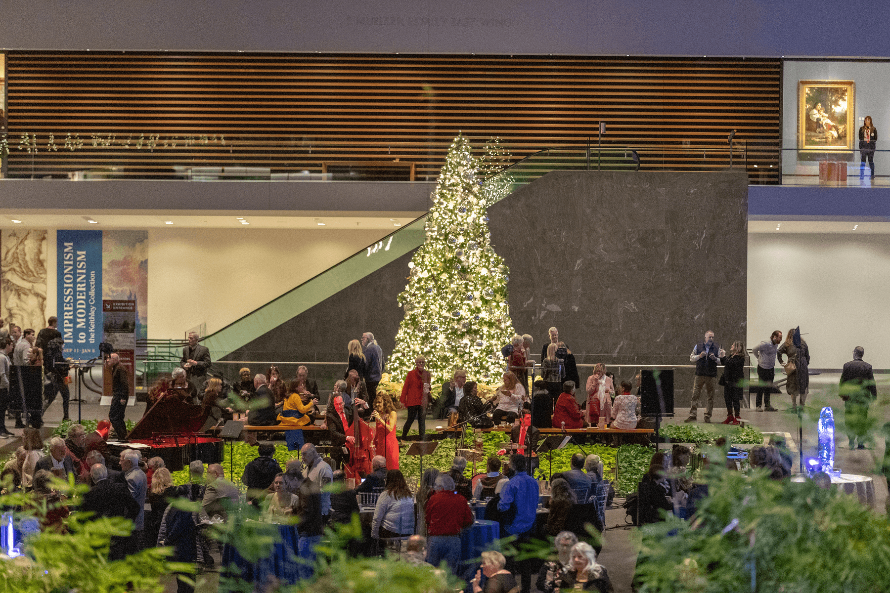 a group of people sitting on the stairs in front of a christmas tree