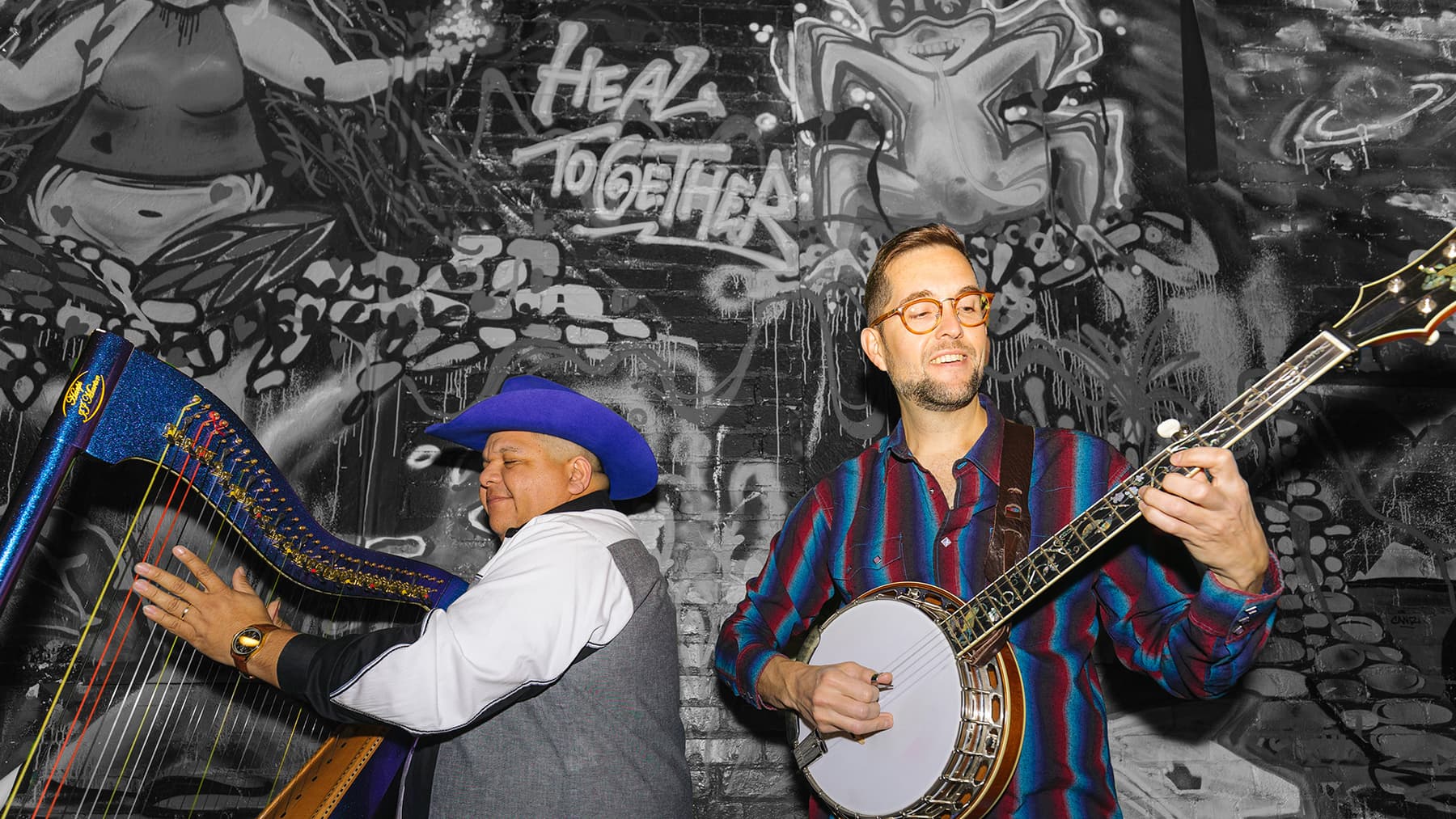 a person playing a guitar next to a person with a hat