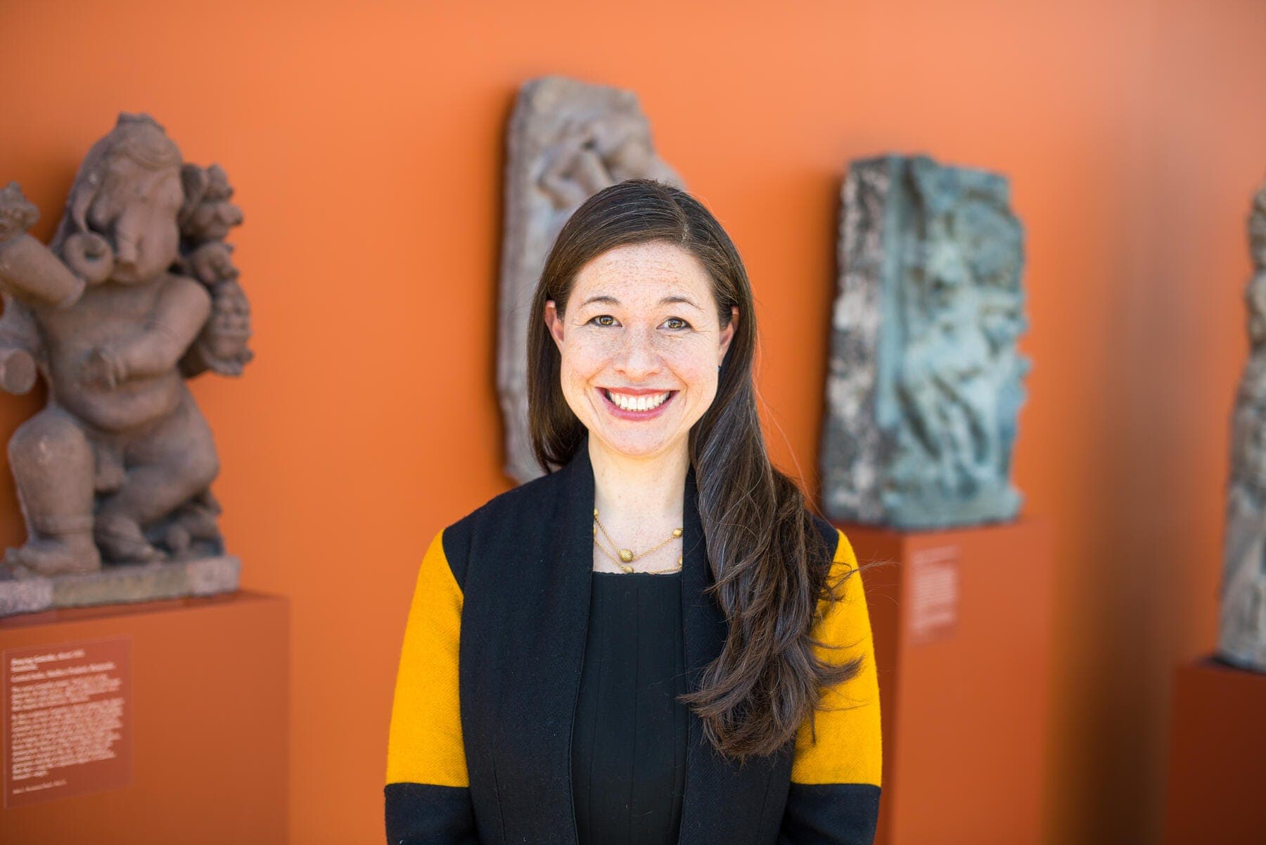 a person smiling in front of a statue