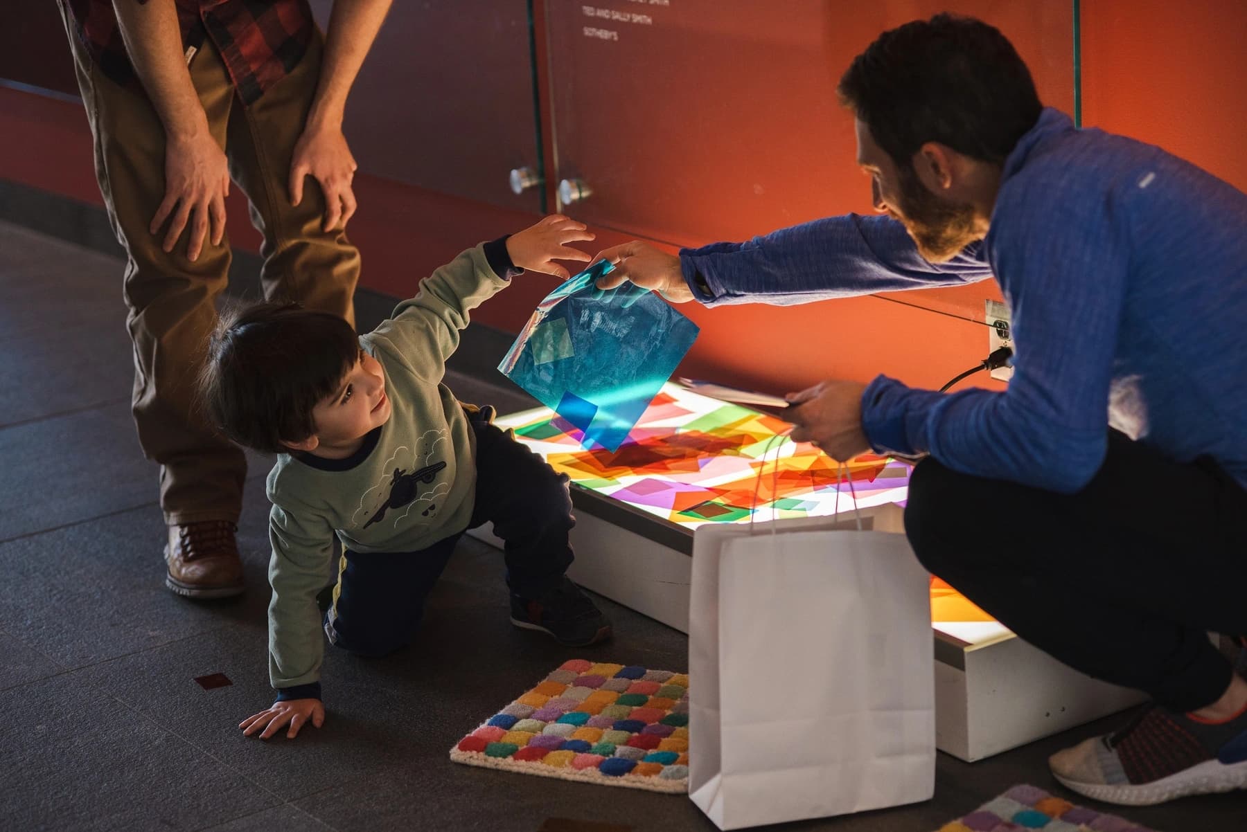 A child and parent playing with a light box and colored cellophane.