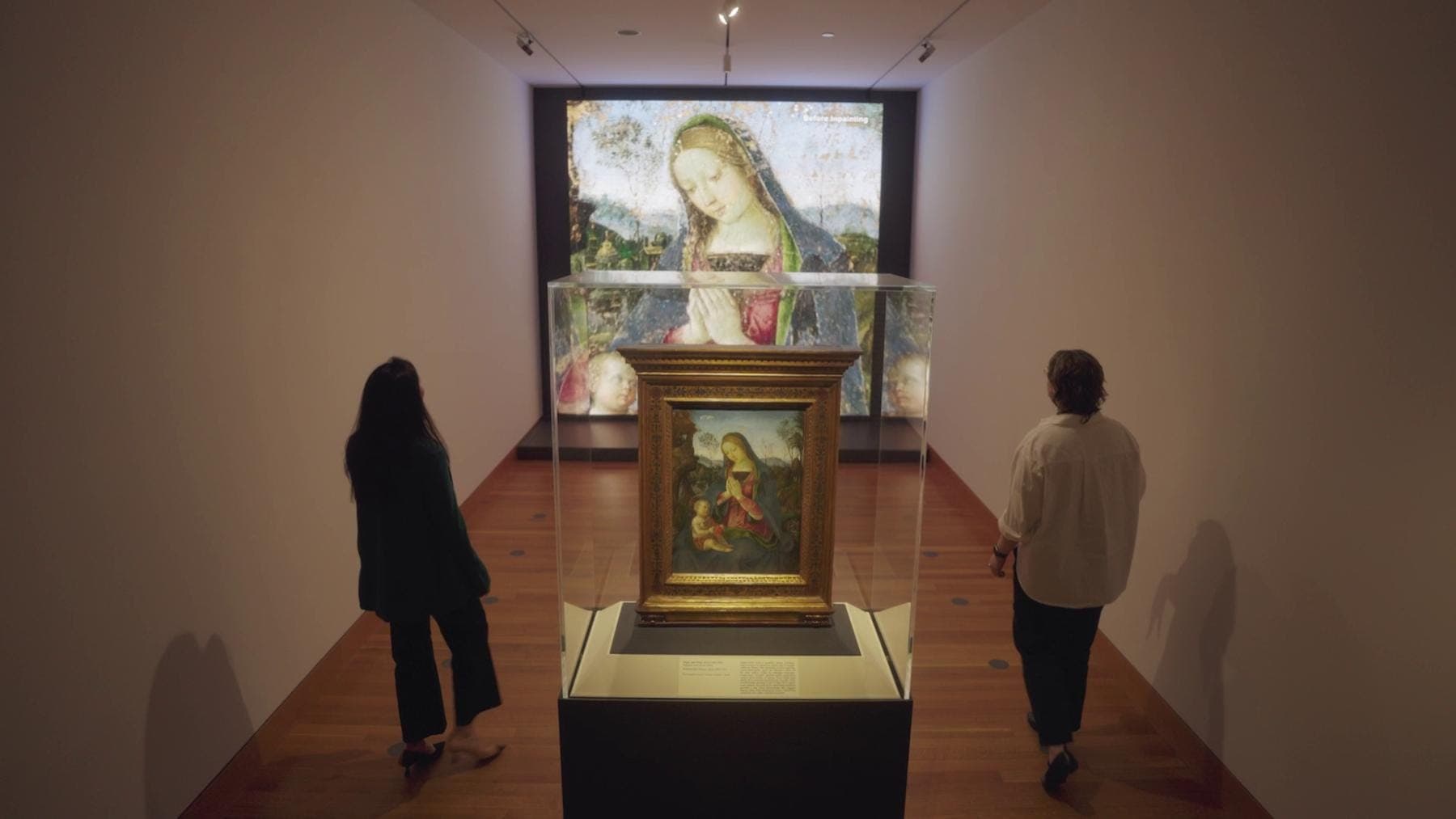 a couple of people looking at a painting on a wall