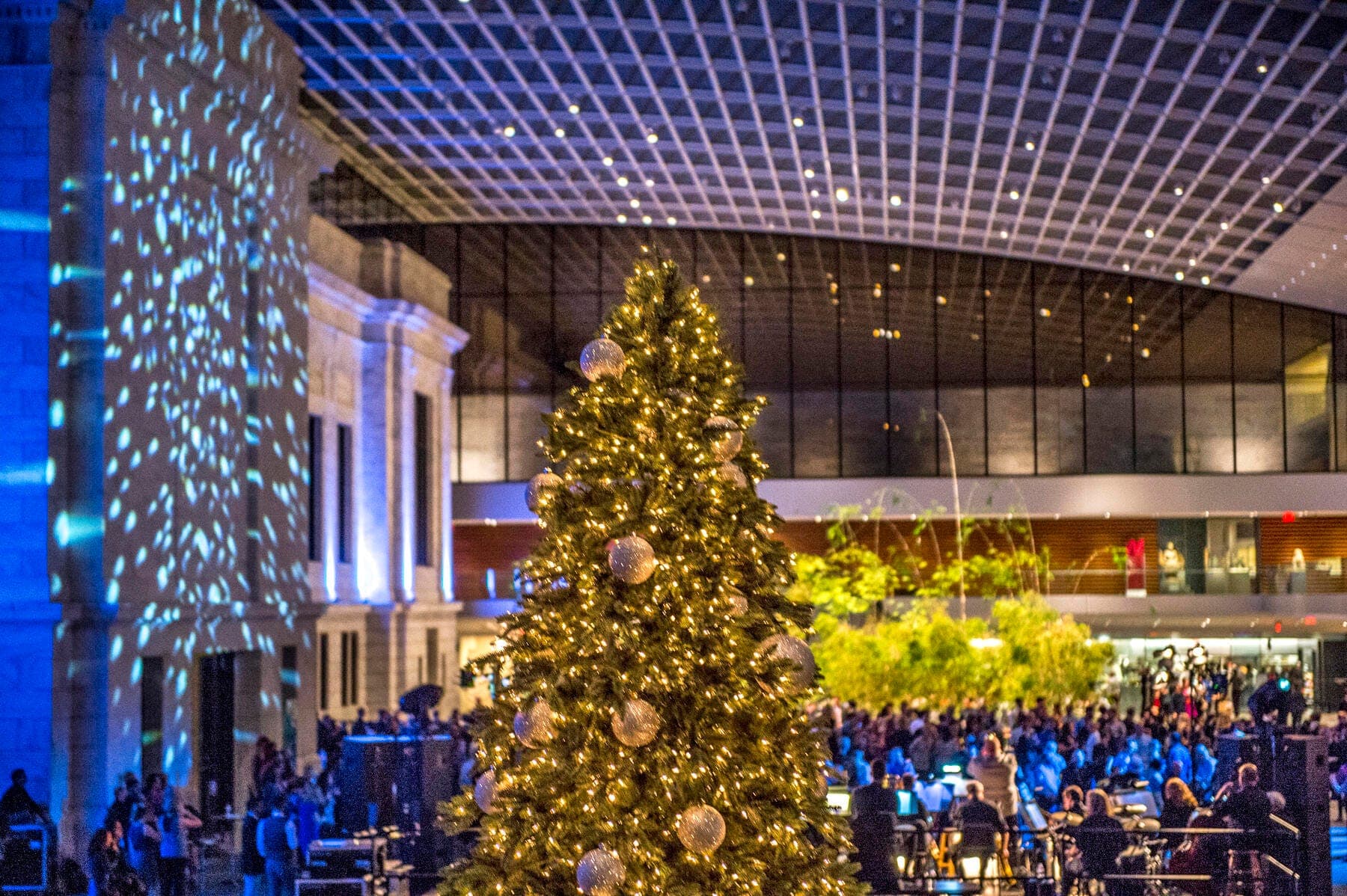 a large crowd of people in a large building with a large christmas tree
