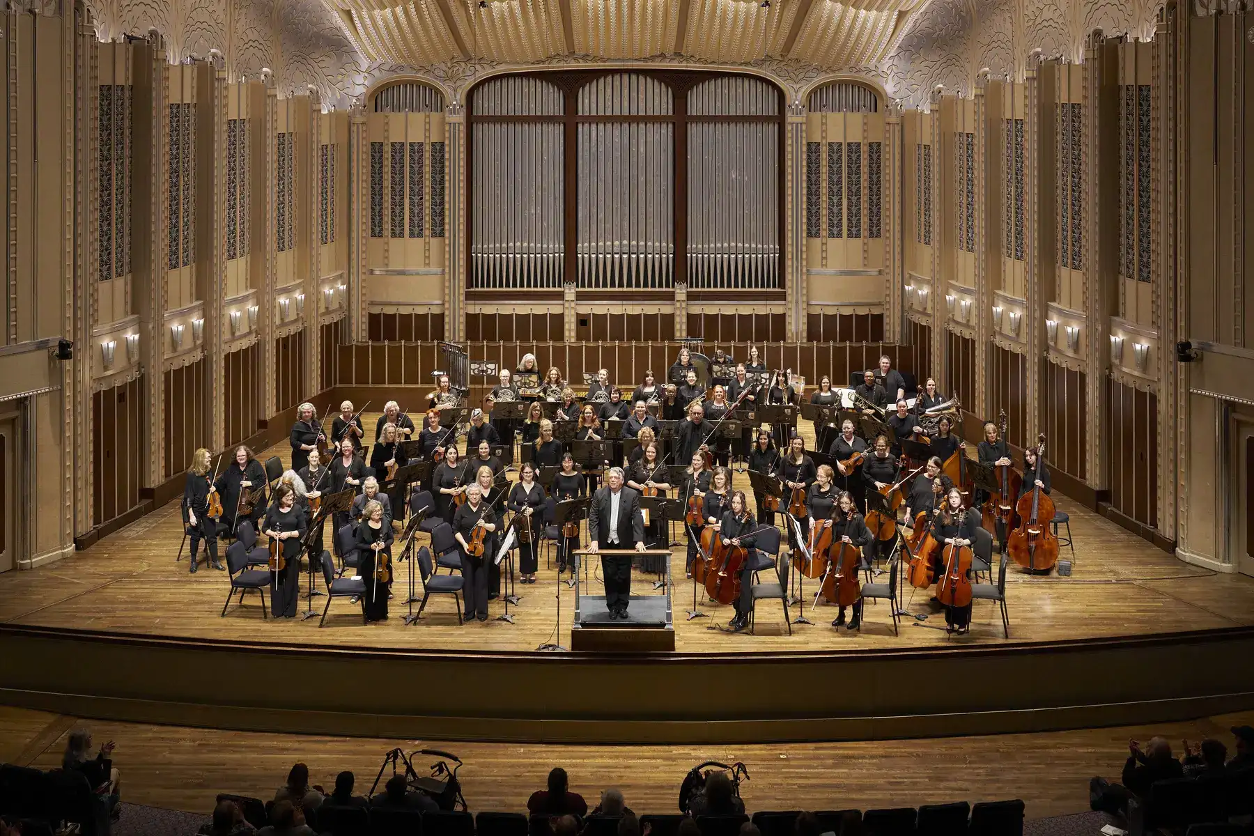 a group of people playing instruments in a large room with a large group of people