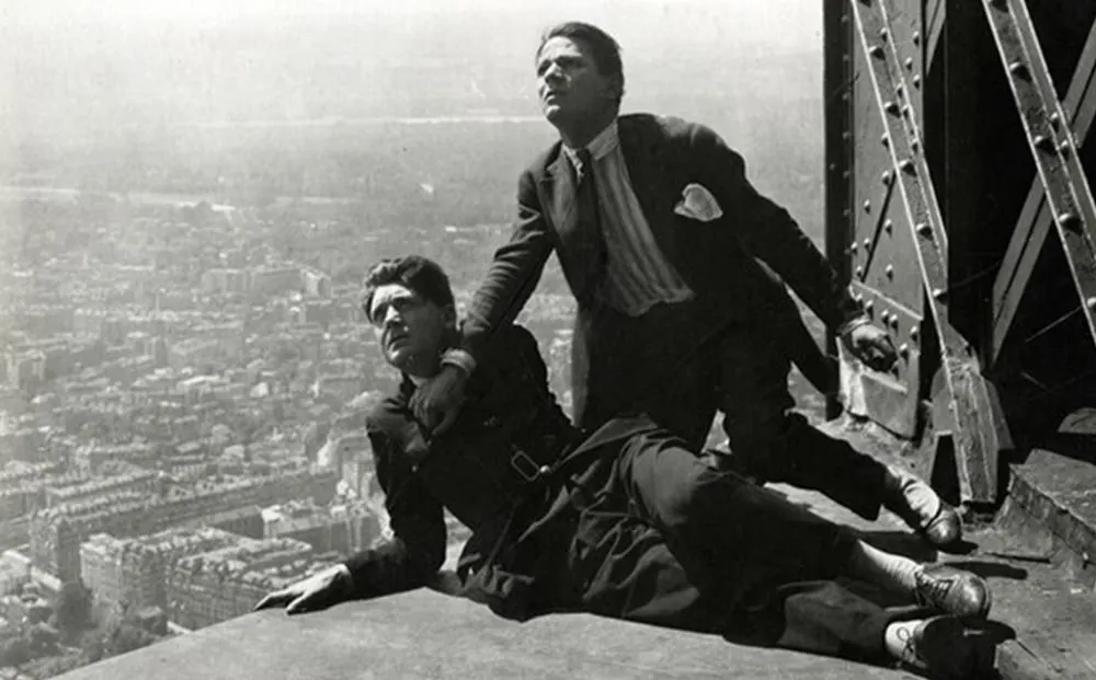 a man sitting on a ledge with a man standing on a roof