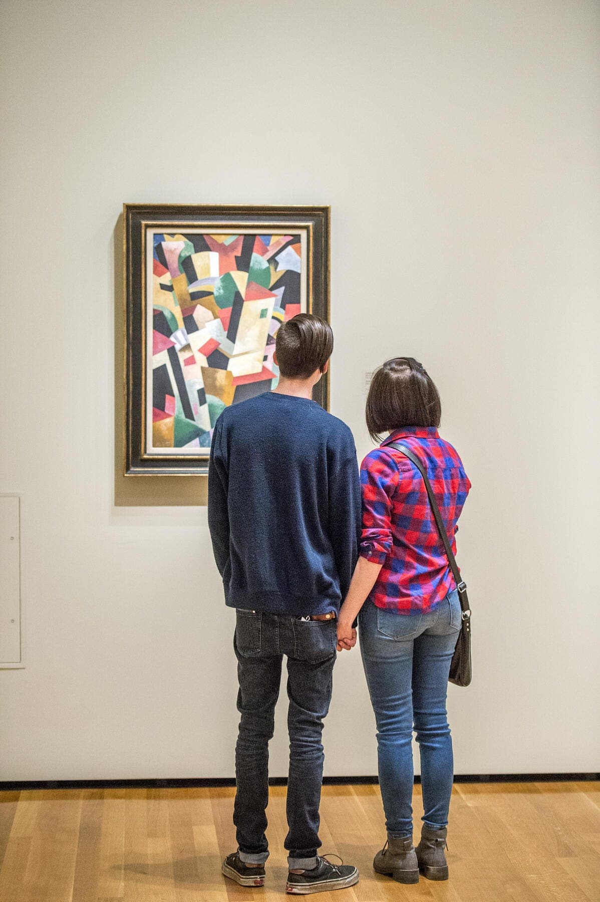 a man and woman looking at a painting on a wall