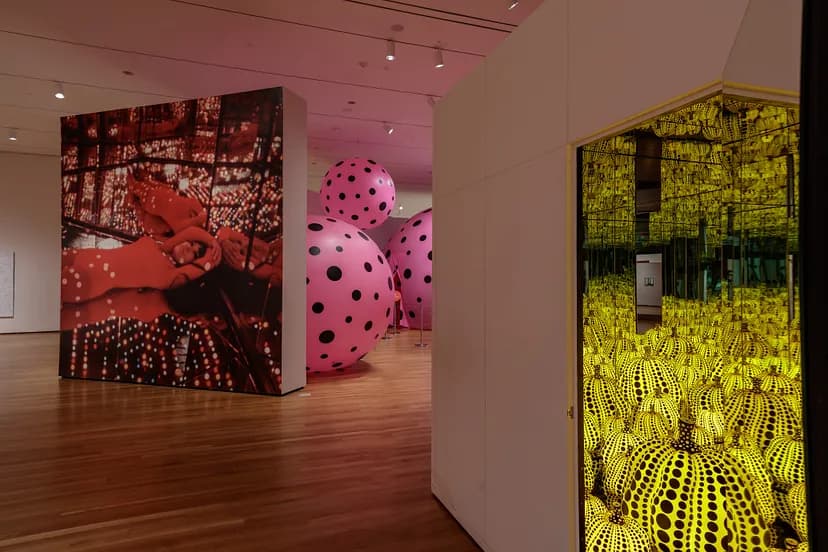 Installation image of Yayoi Kusama: Infinity Mirrors with wall-height red, pink, and yellow artworks.