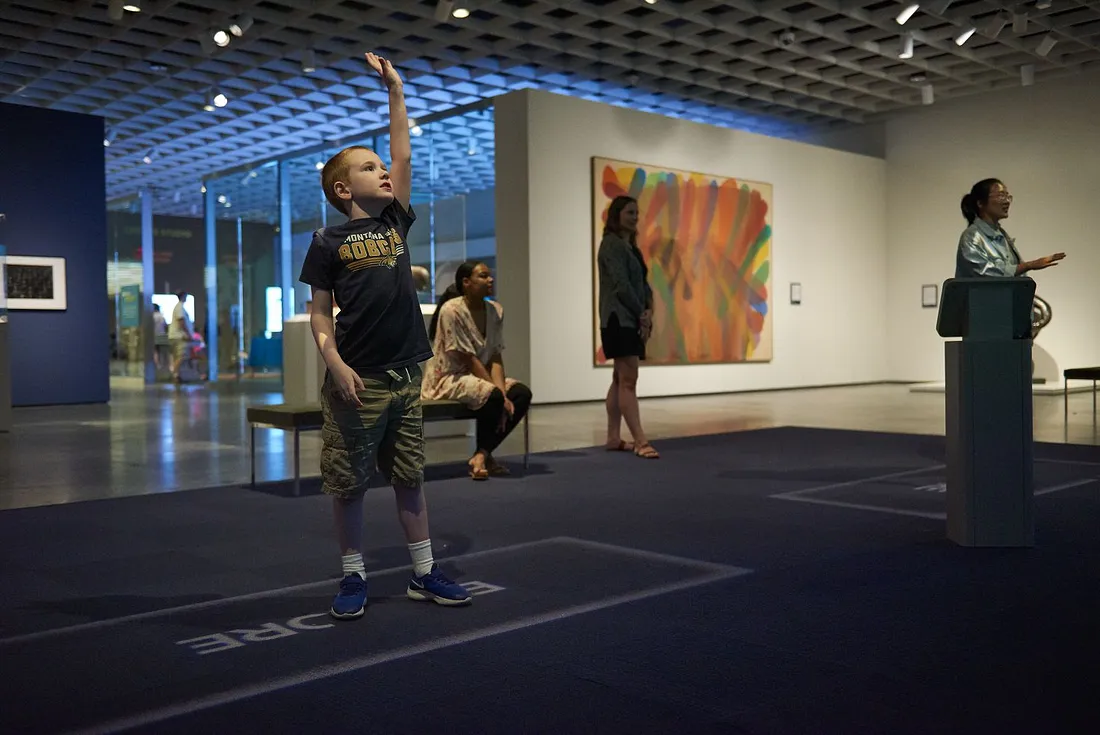 People in ArtLens Exhibition waving their arms ad they play the games.