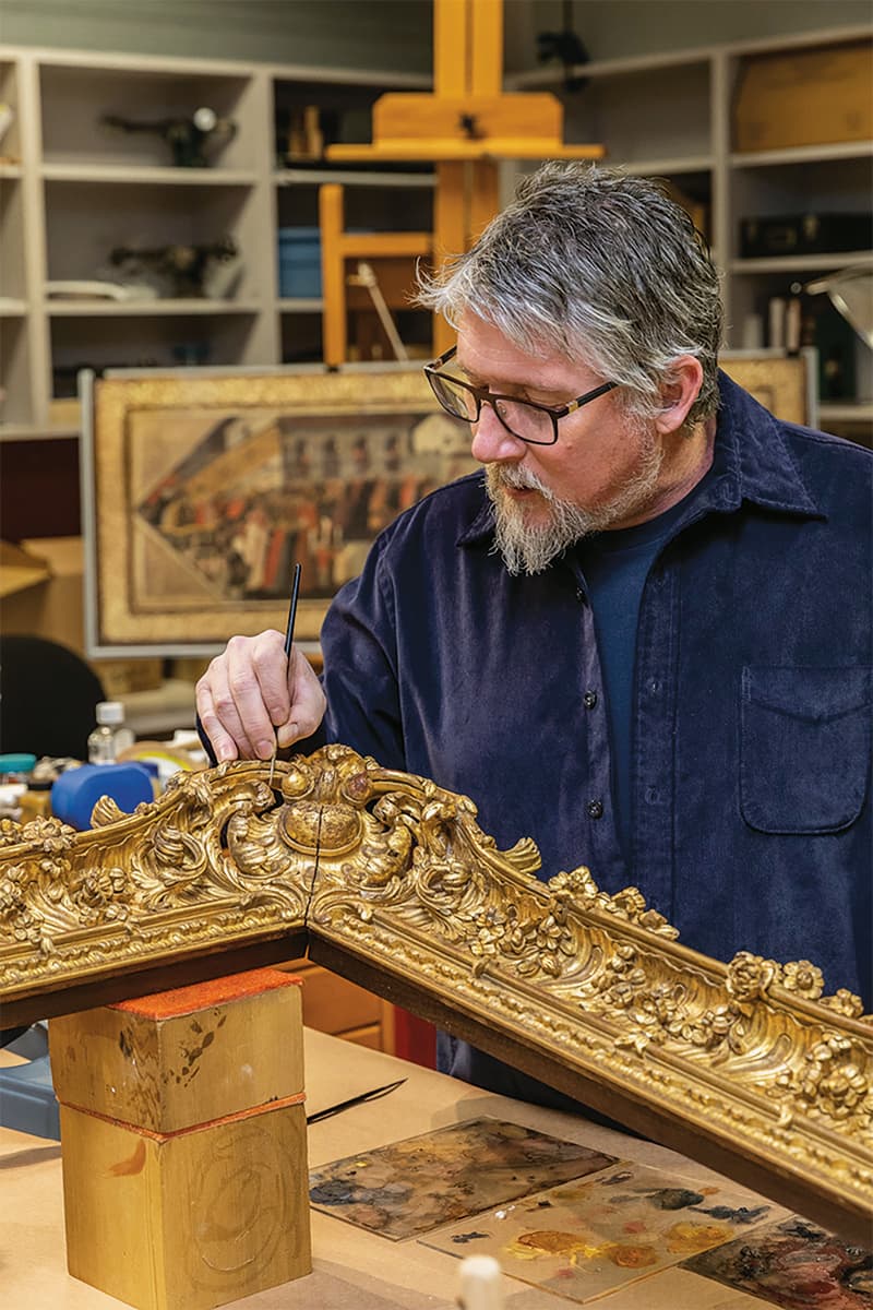 man cleaning art frame in studio
