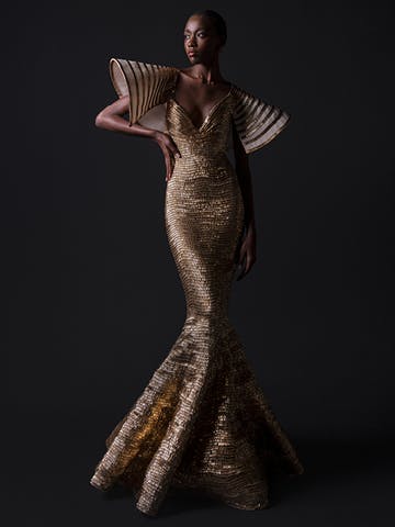 Model poses in long gold textured gown