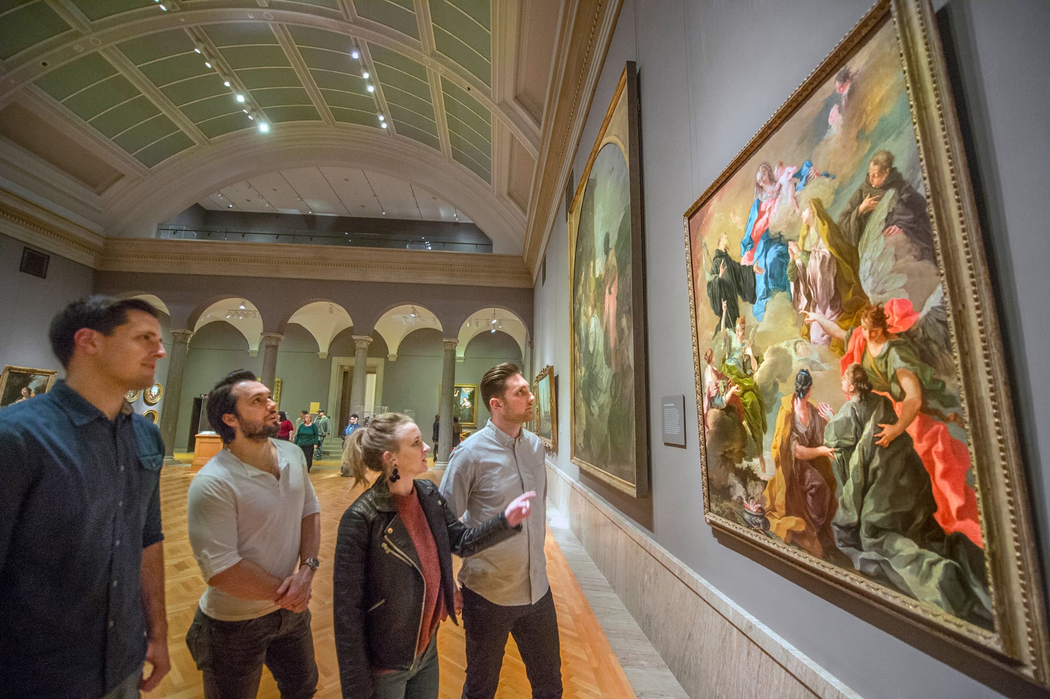 Four adults viewing a painting in the museum galleries