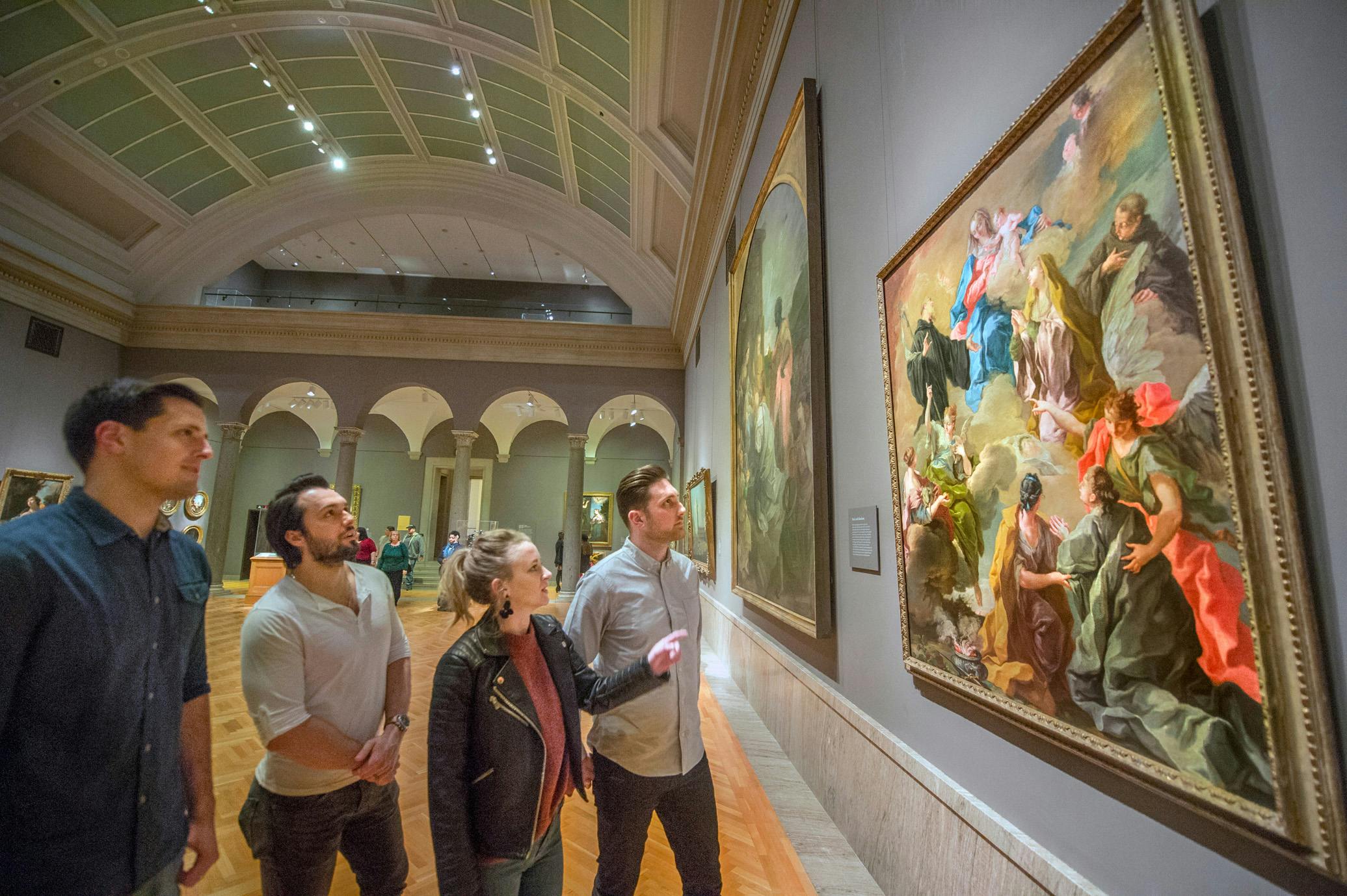 Four adults viewing a painting in the museum galleries