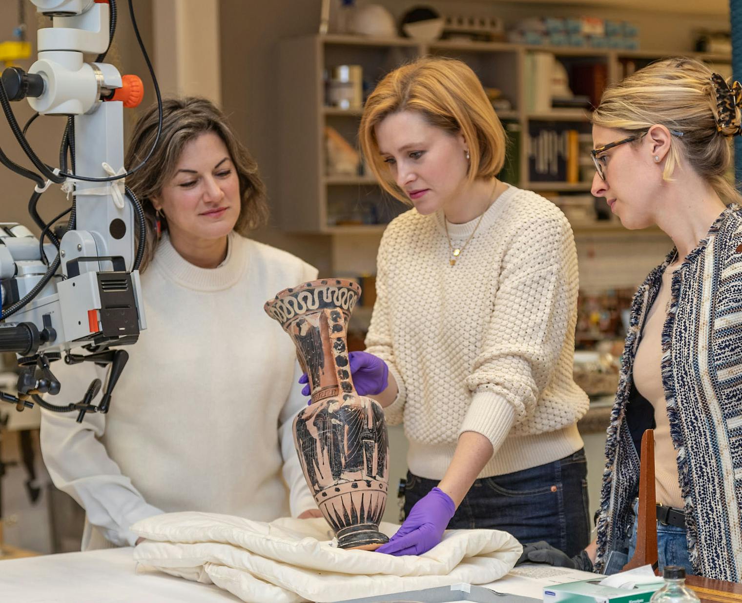 Preventive and objects conservators examining a Greek vase in the objects conservation lab