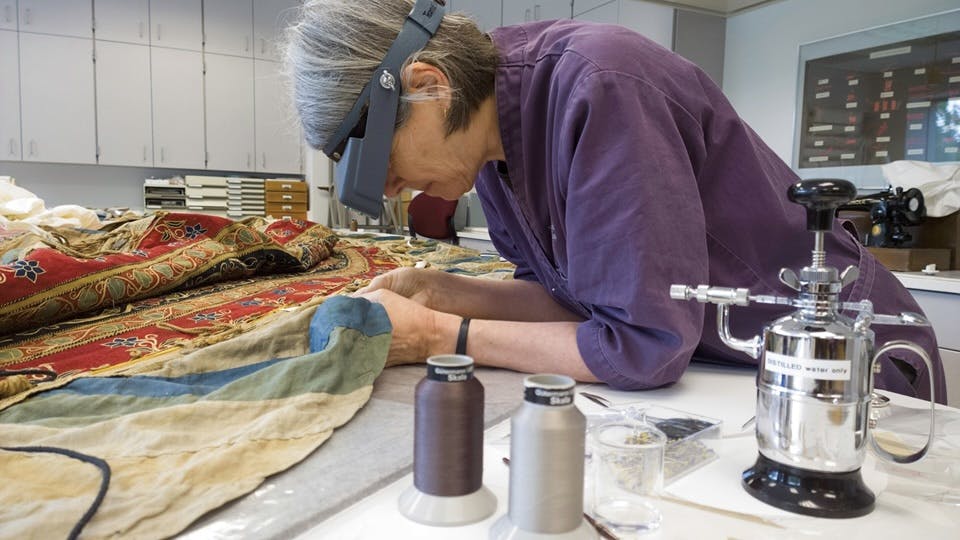 Conservator of Textiles, Robin Hanson, working in the textile conservation lab.
