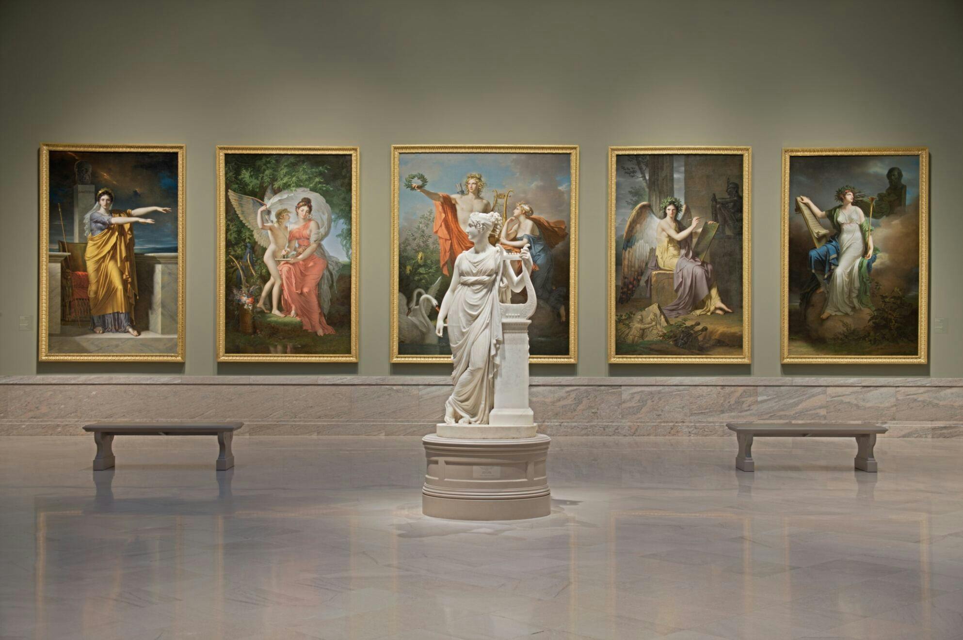 A statue in the CMA standing in front of a wall of paintings