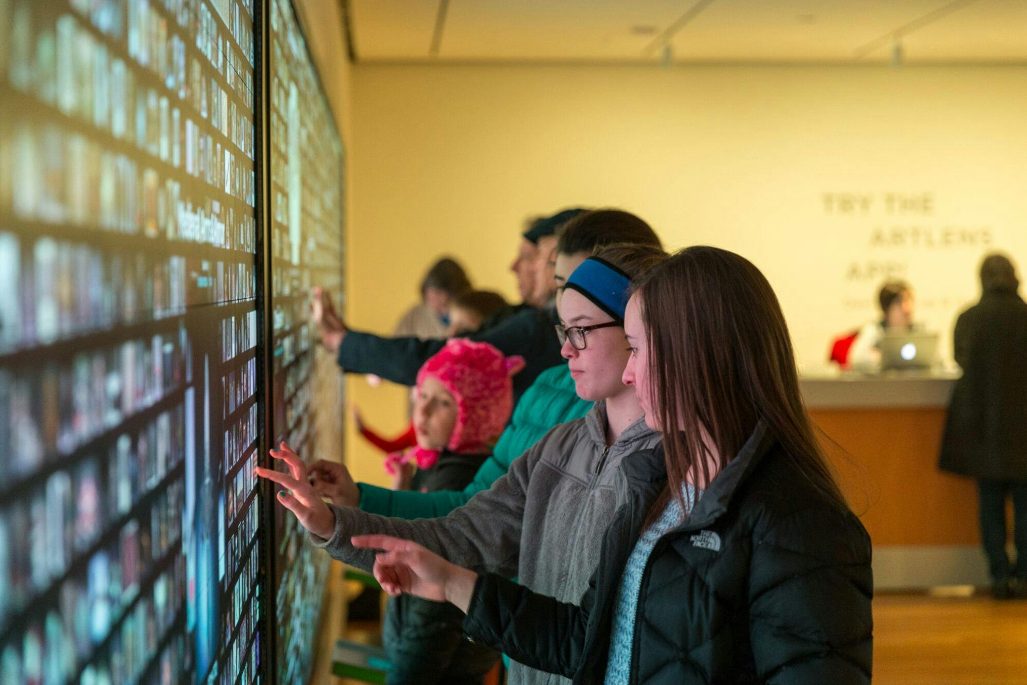 Visitors interacting with a touchscreen on the wall
