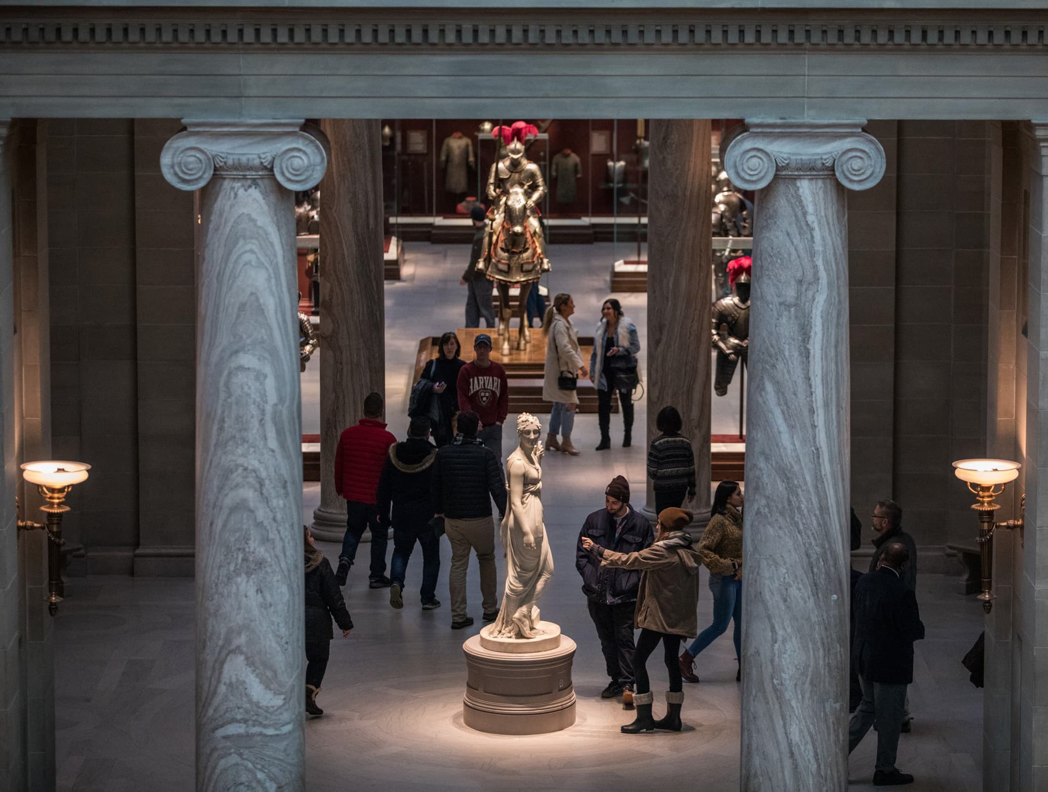 groups of people in an art gallery with marble sculpture and architecture