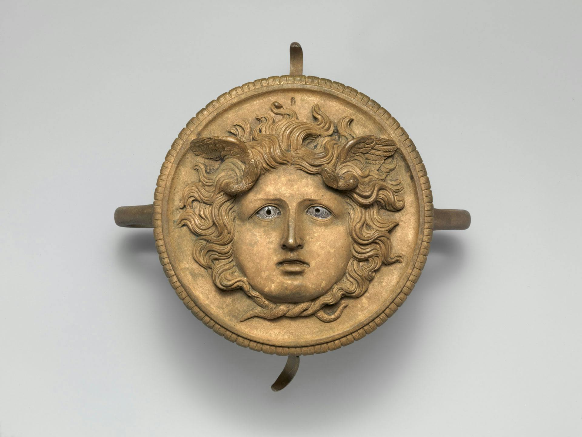 a round bronze ornament with a face