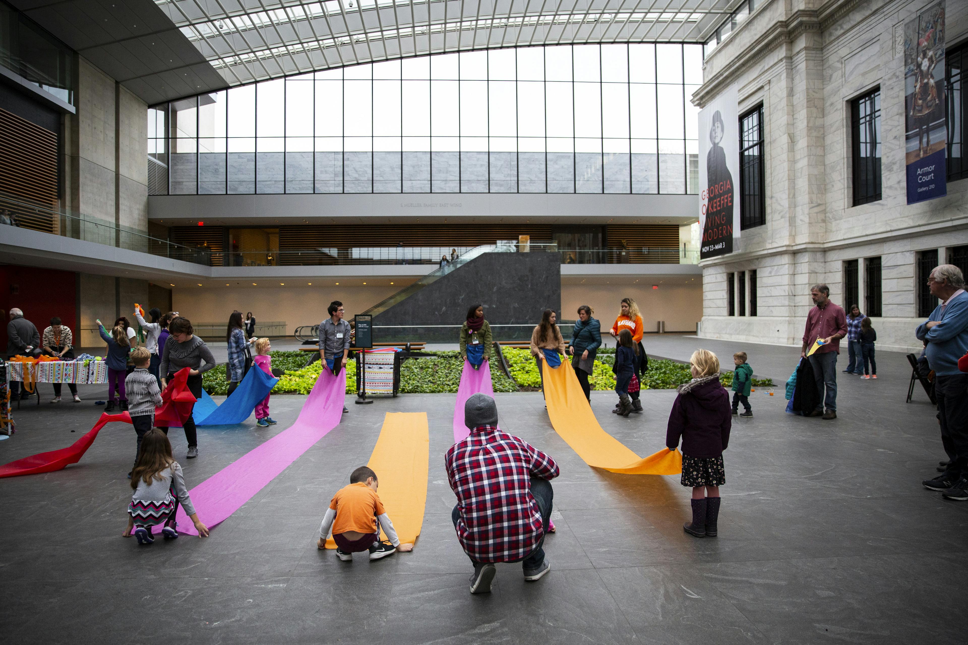 Families playing with large strips of fabric in the atrium
