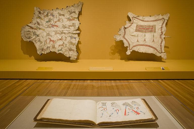 Gallery view with a book in the foreground and animal skins in the background