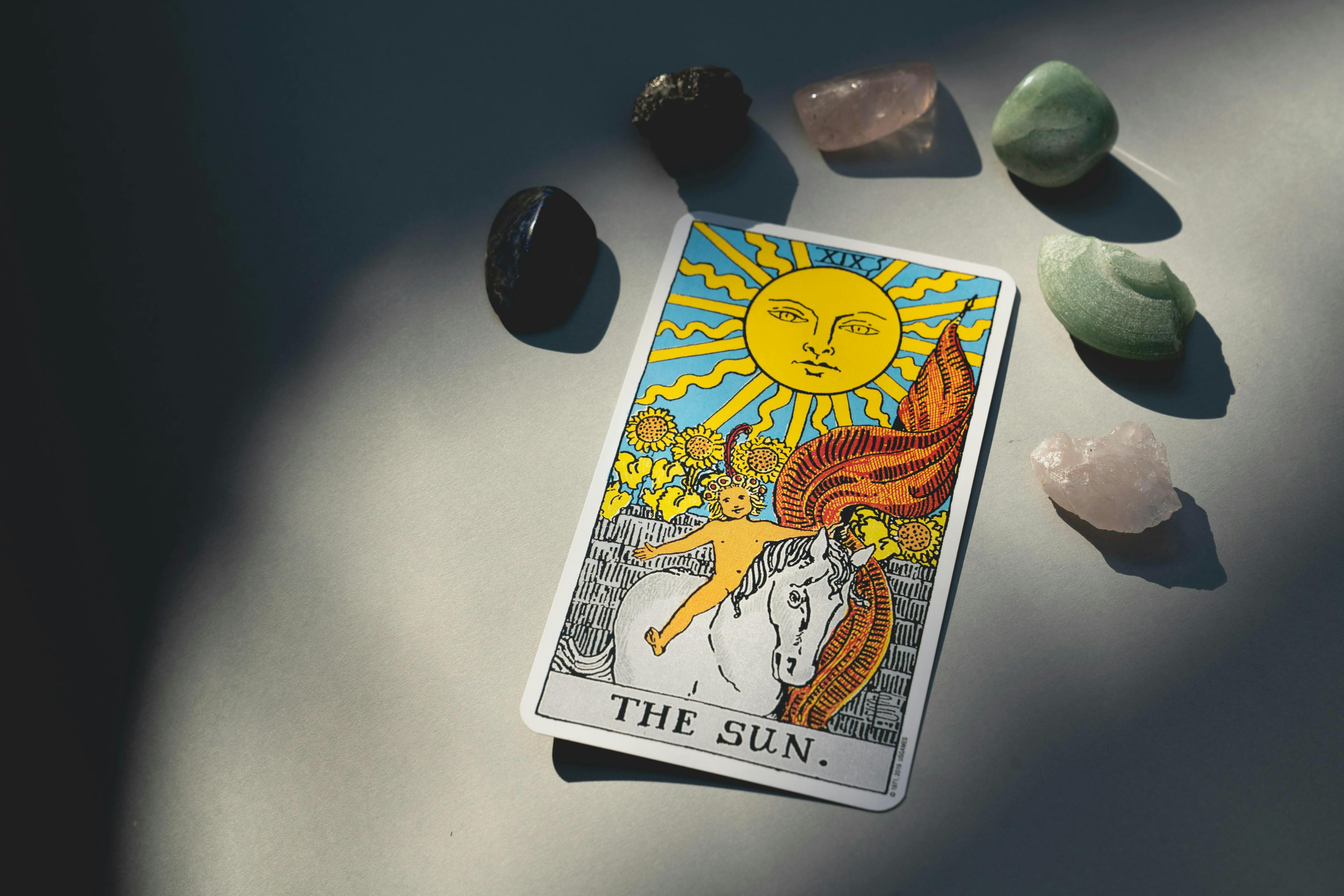 Image of a tarot card depicting the sun and surrounded by crystals.