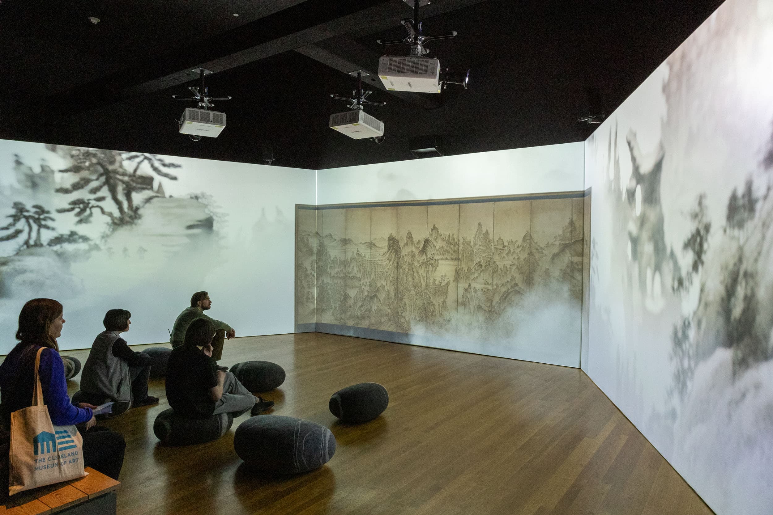 people sitting in a room amidst a large immersive projection