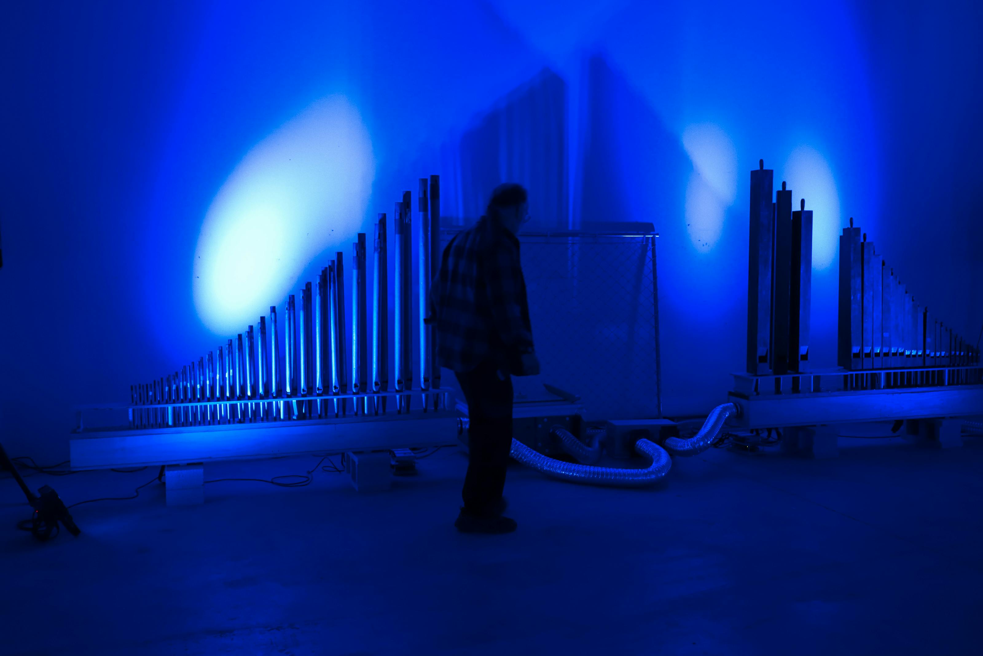 Artist standing in front of reclaimed organ pipes for a sound installation.
