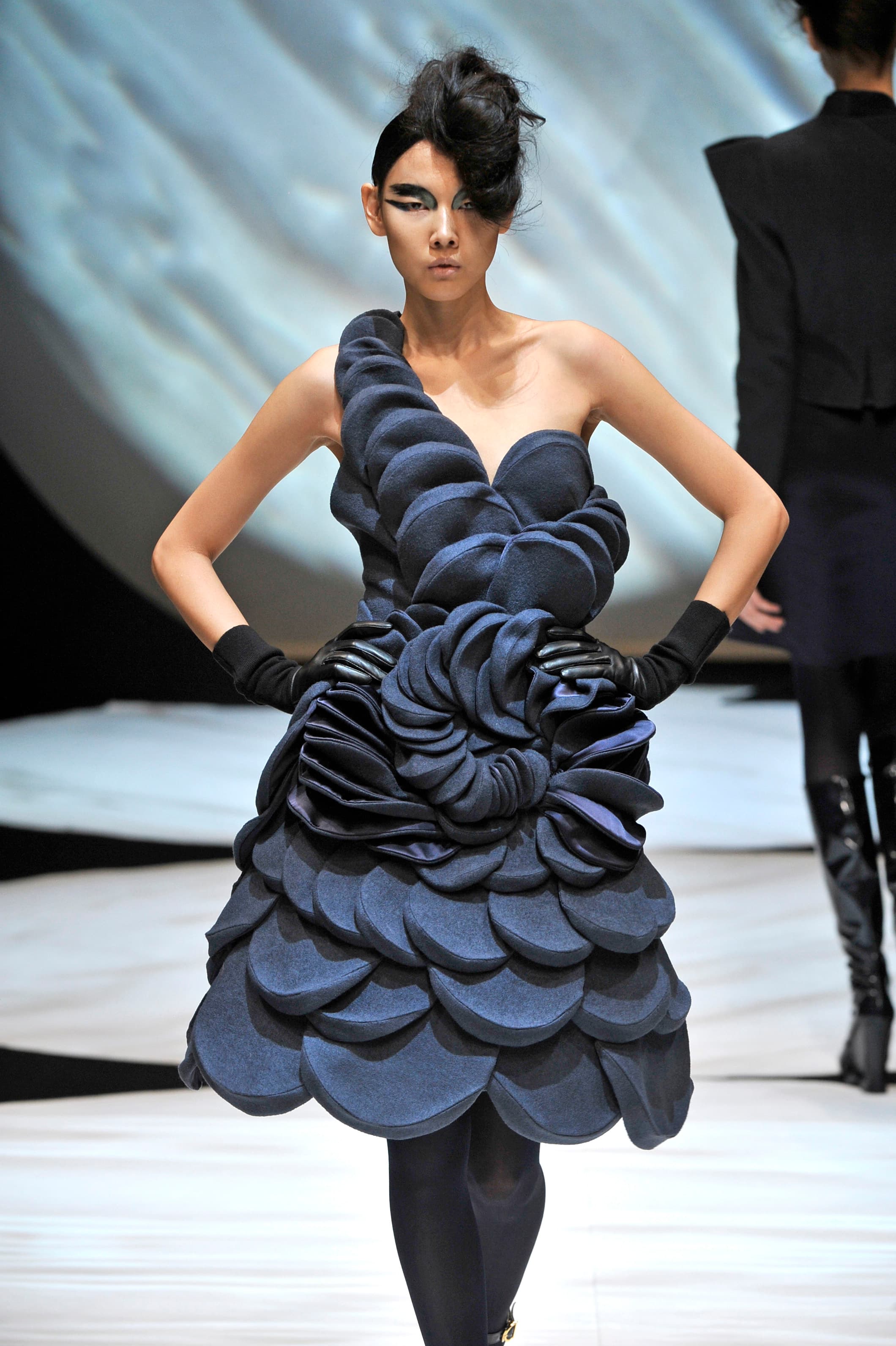 Model walking down a runway wearing black dress