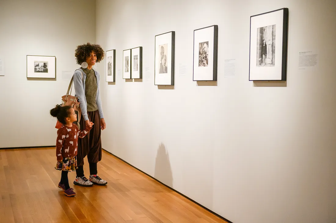 An adult and child looking at photographs in the exhibition Gordon Parks: The New Tide, Early Work 1940–1950.