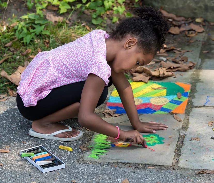 Child writing on ground with chalk.
