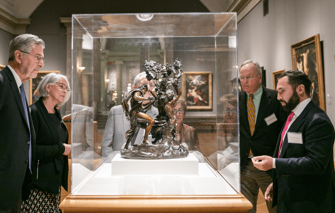 a group of museum patrons discussing a sculpture