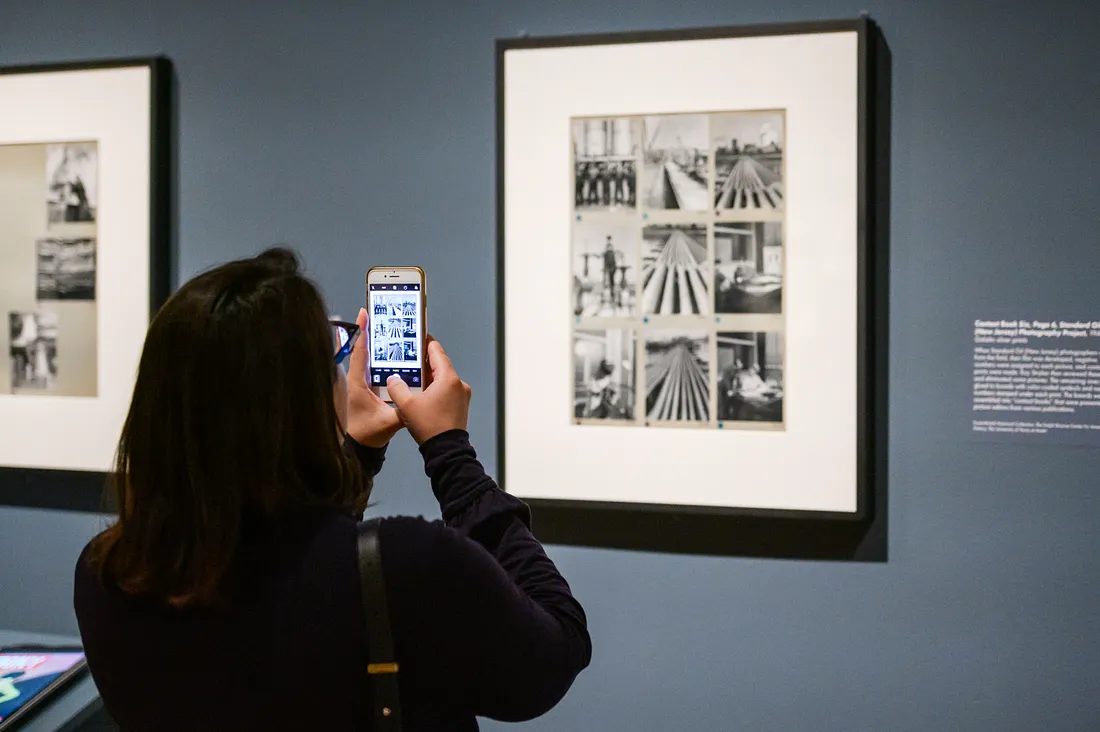 Back of a visitor taking a picture of a photograph with their phone in the exhibition Gordon Parks: The New Tide, Early Work 1940–1950.