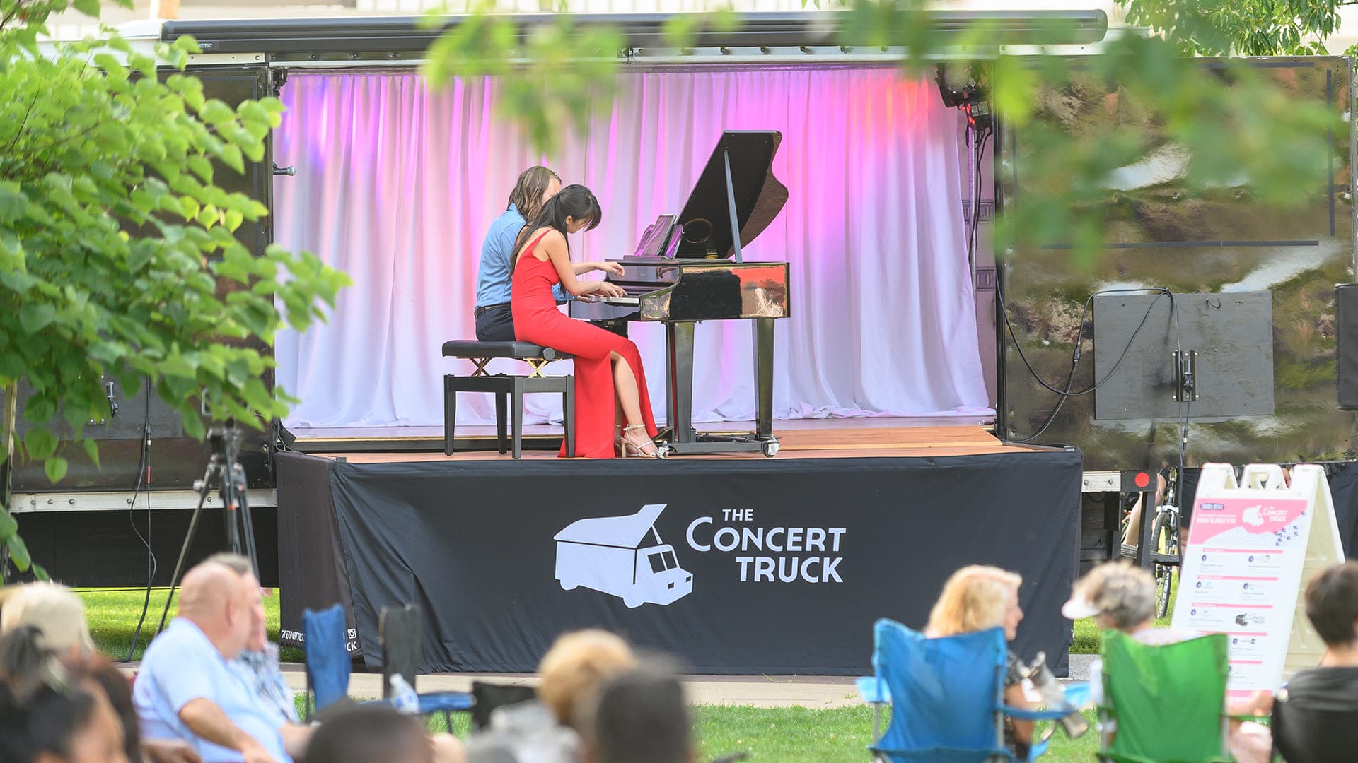 Image of stage with a pianist and baby grand piano.