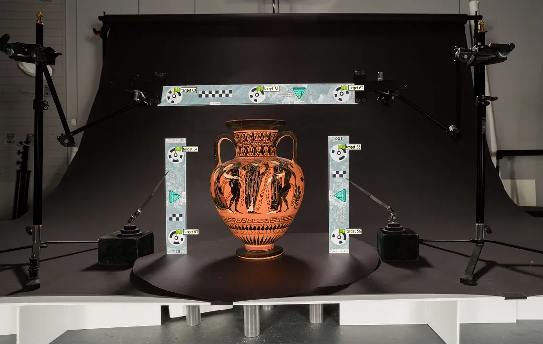 A neck amphora, like a vase with a rounded base, narrow neck, and handles on each side, set up to be photographed in front of a black background.