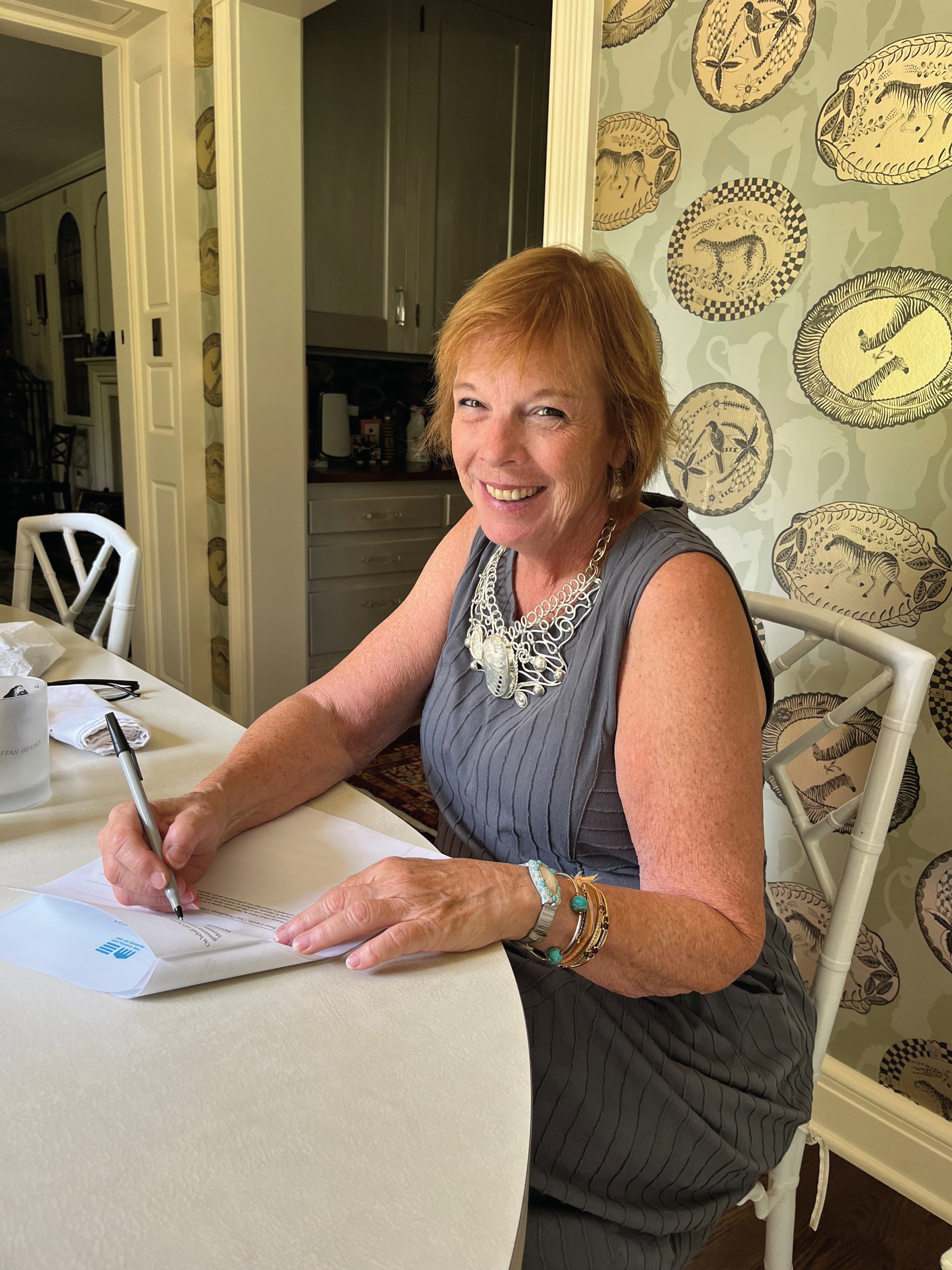 woman at table writing with pen