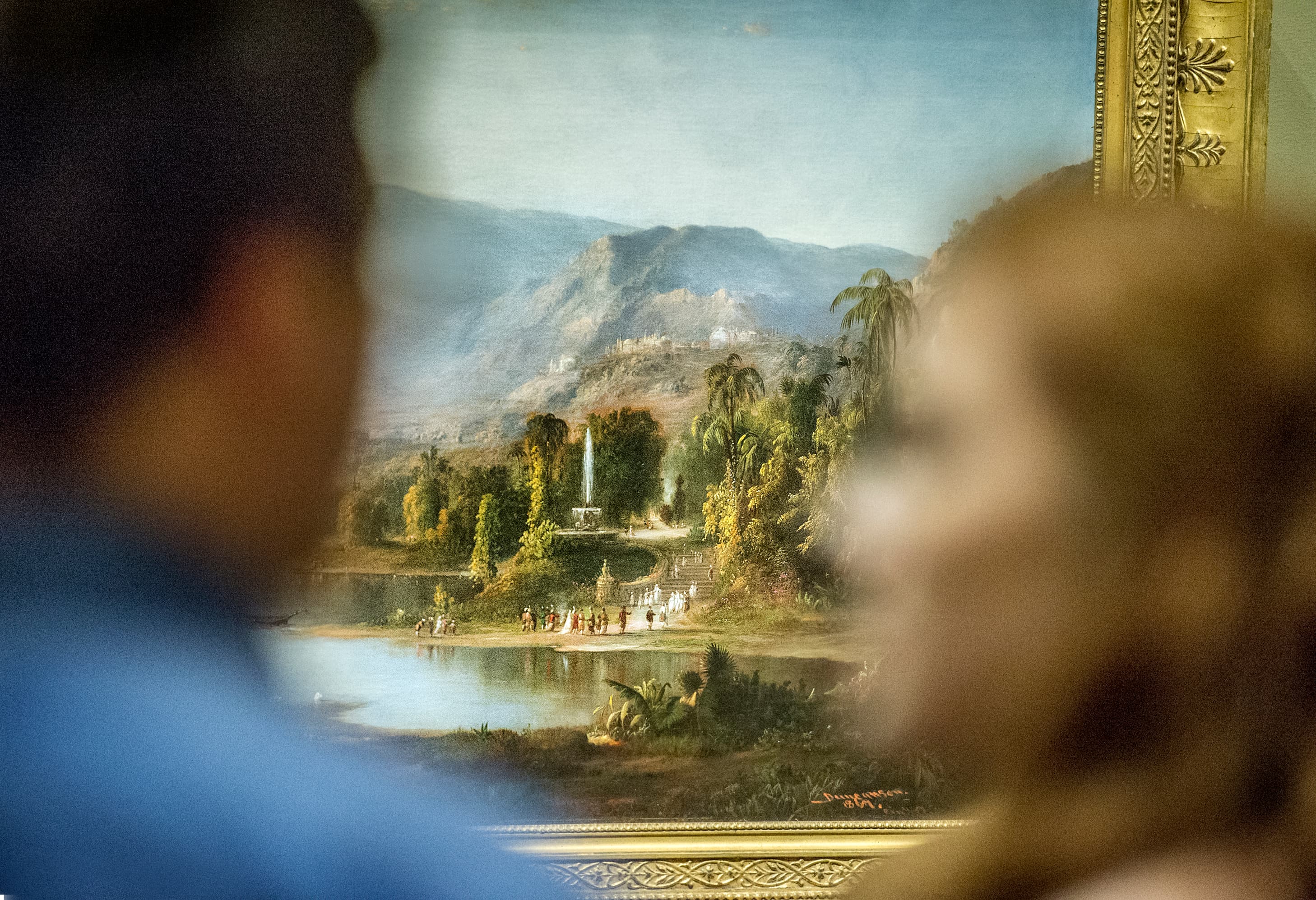 Two figures are in the foreground with a landscape painting in the background